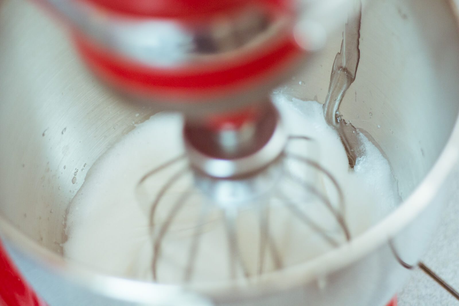 Когда сироп достигнет 116°C (240.8°F), аккуратно, тонкой струйкой влейте его по краю чаши миксера.